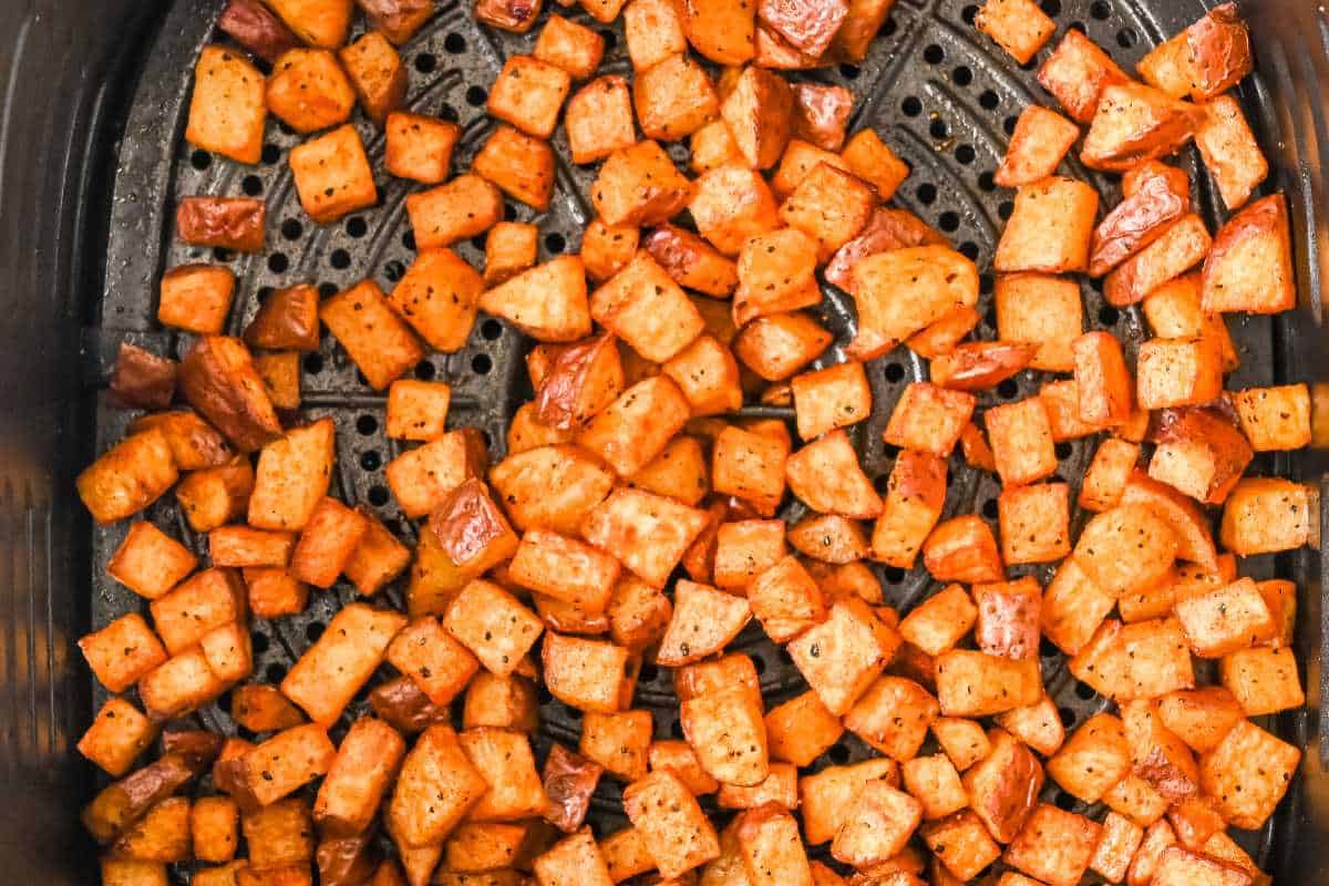 cooked red potatoes in a black air fryer basket.