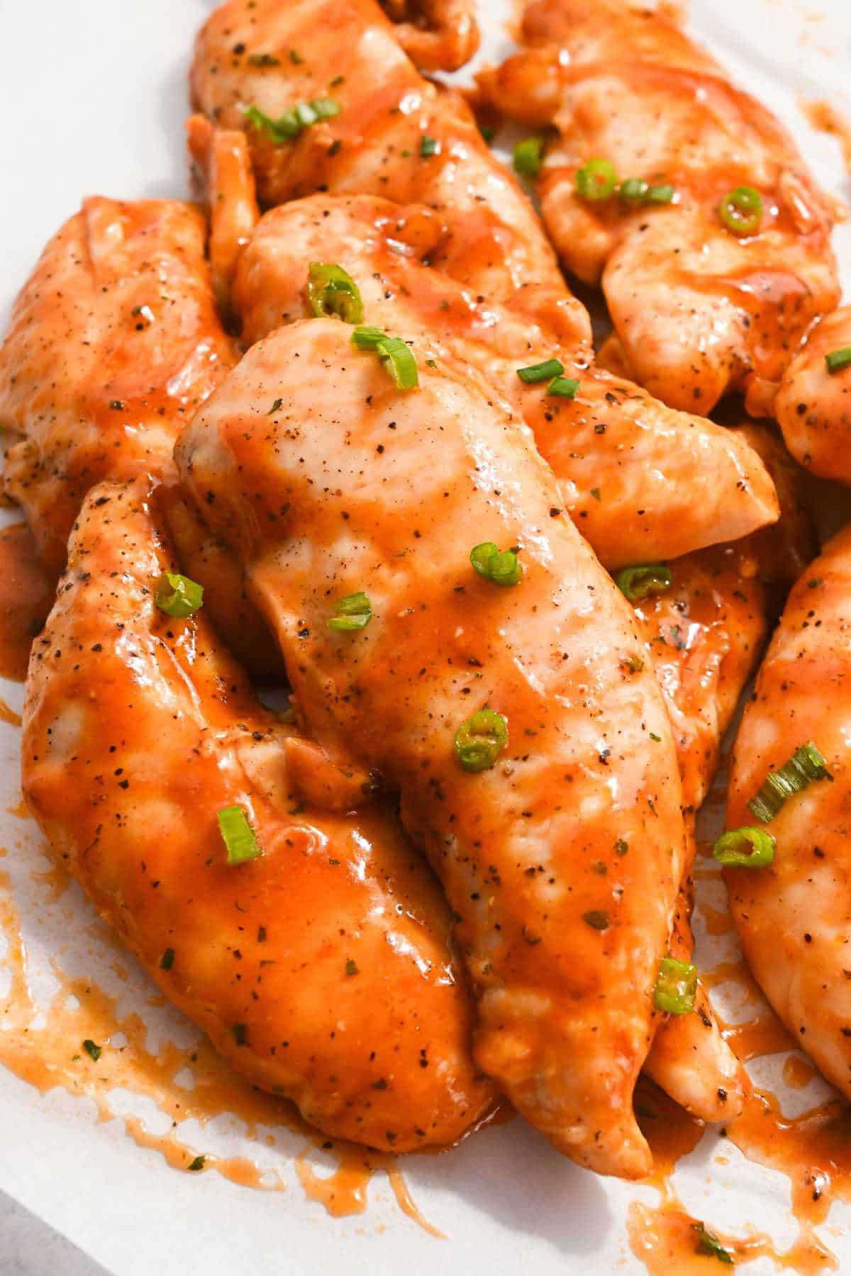 buffalo sauce on chicken tenders topped with green onions.