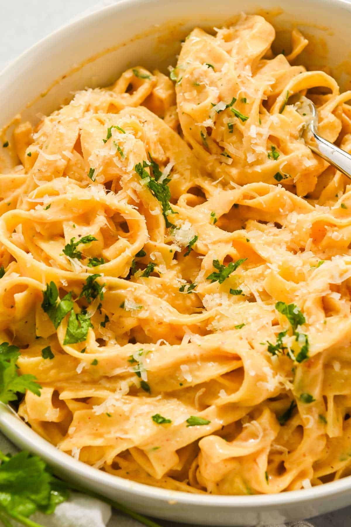 bowl of fettuccine and cajun pasta topped with parsley.