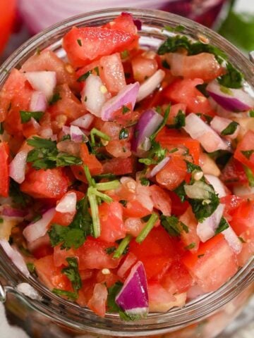 close up of mild pico de gallo salsa in a glass jar.