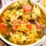 close up of chicken and rice soup in a white bowl.