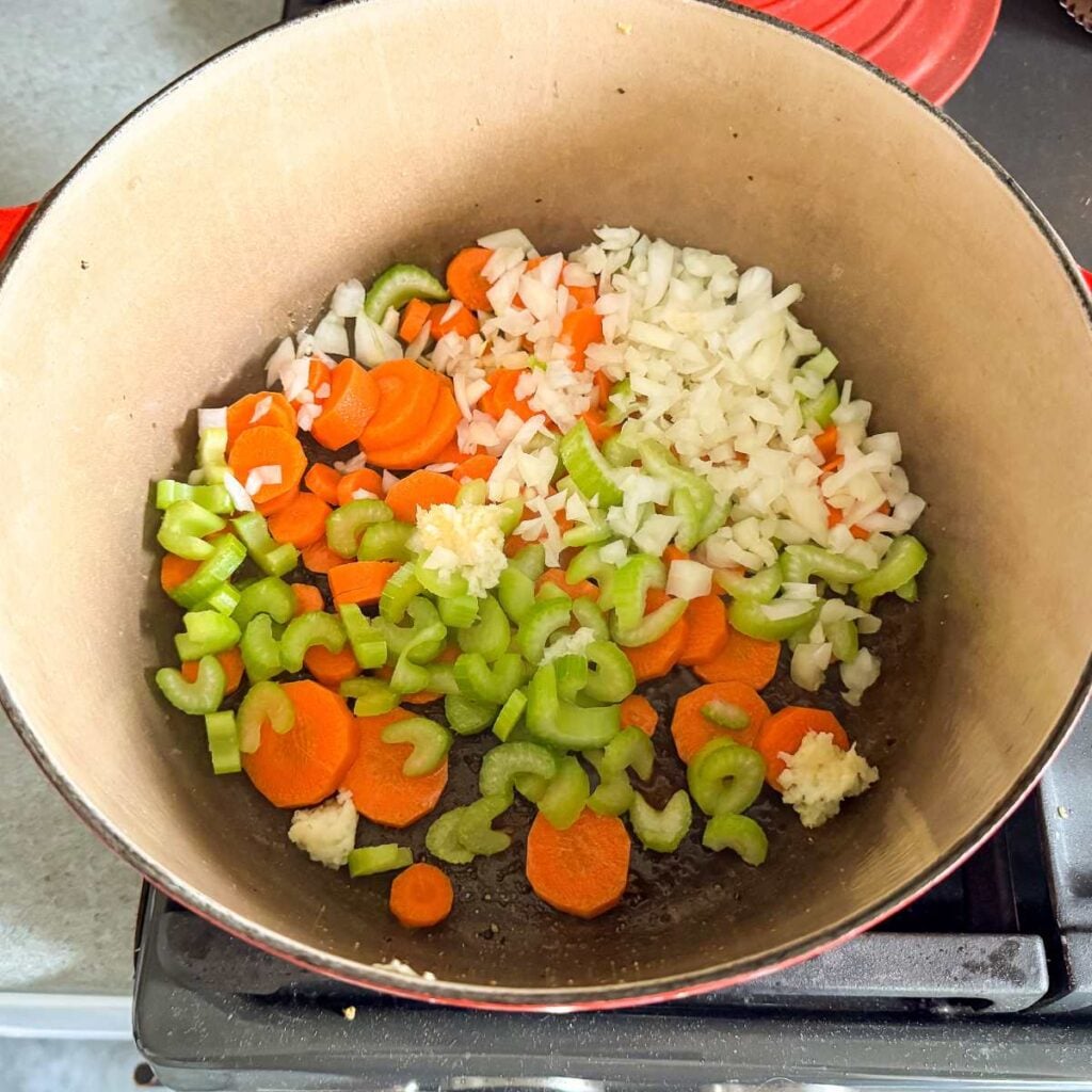 raw celery, carrots, onions, and garlic in a Dutch oven.