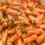 close up shot of lobster bisque pasta topped with fresh basil and parmesan cheese.