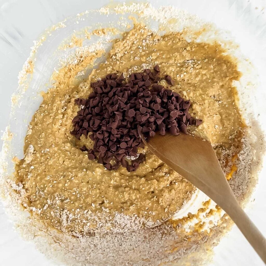 wooden spoon stirring mini chocolate chips into a bowl.